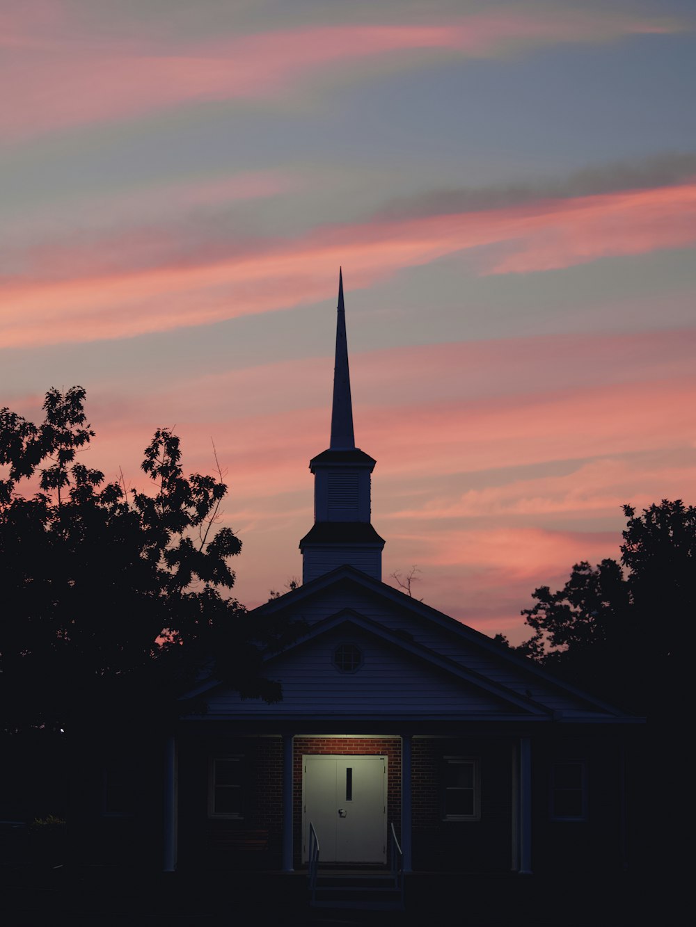 a church with a steeple at sunset