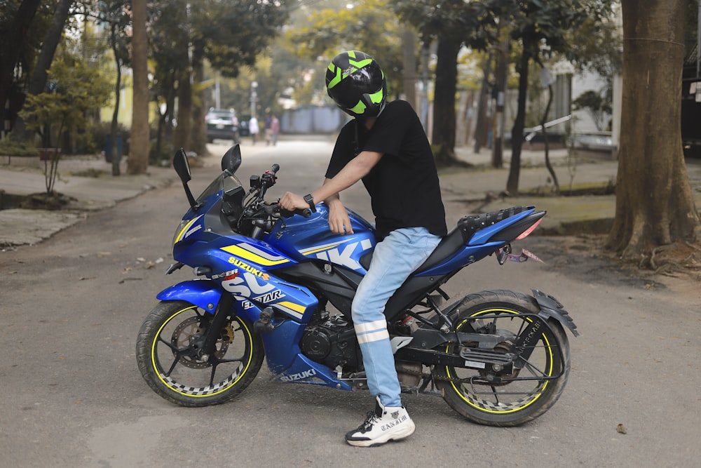a man wearing a helmet sitting on a blue motorcycle