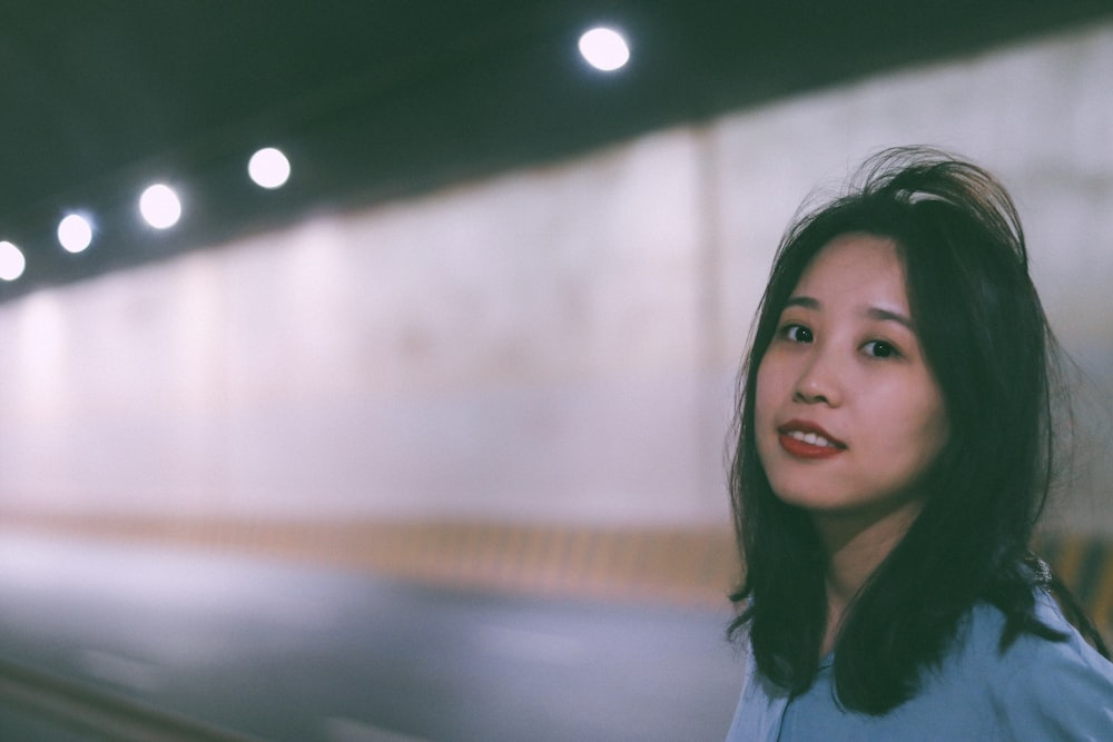 a woman in a blue shirt standing in front of a wall