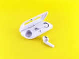 Close-up of a stylish yellow wireless earbud case on a minimalist white background.