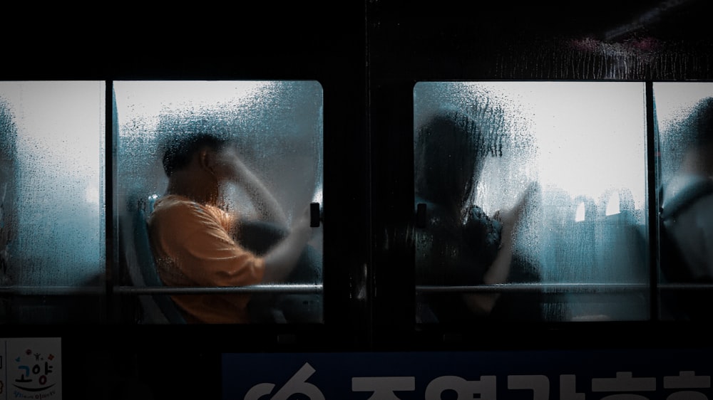 a man sitting on a train next to a window
