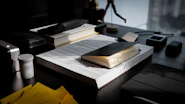 A close-up of a desk with neatly organized files and a red pen marking notes on a document.