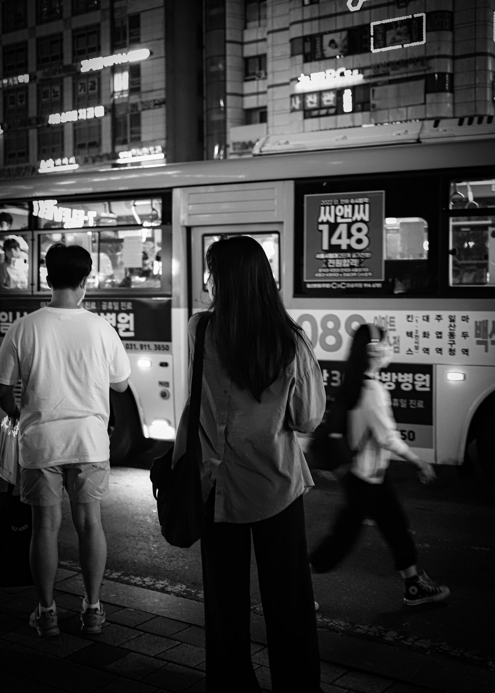 a group of people standing on a sidewalk next to a bus