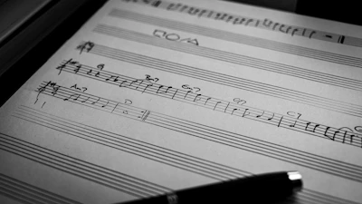A creative composer sketching melodies on a notepad surrounded by instruments.