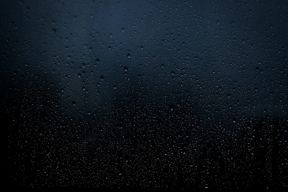 rain drops on a window with a dark background