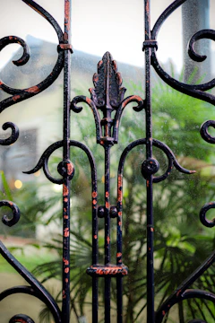 Close-up of a black wrought iron gate opening to a beige stucco house.