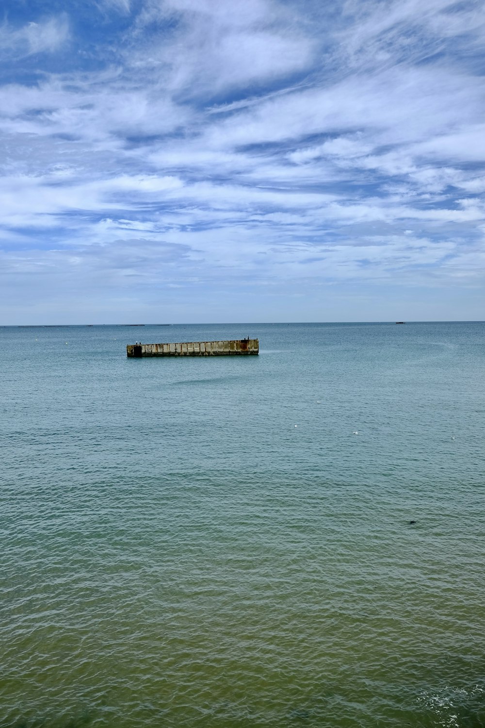 a large body of water sitting under a cloudy blue sky