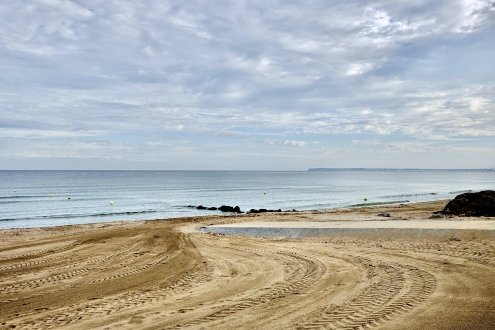 a sandy beach next to the ocean under a cloudy sky