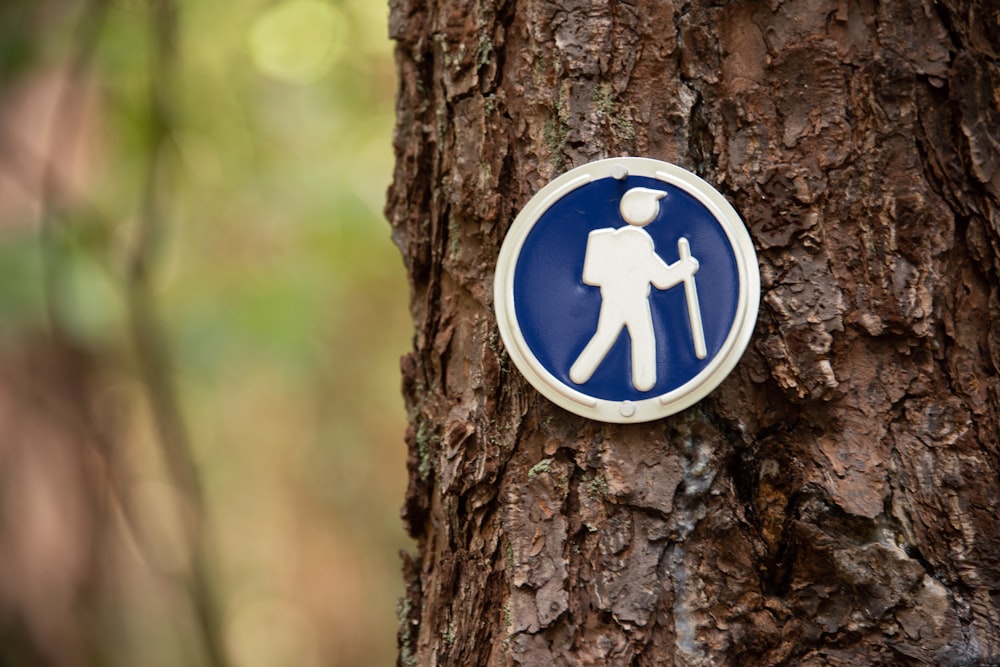 a blue and white sign on the side of a tree