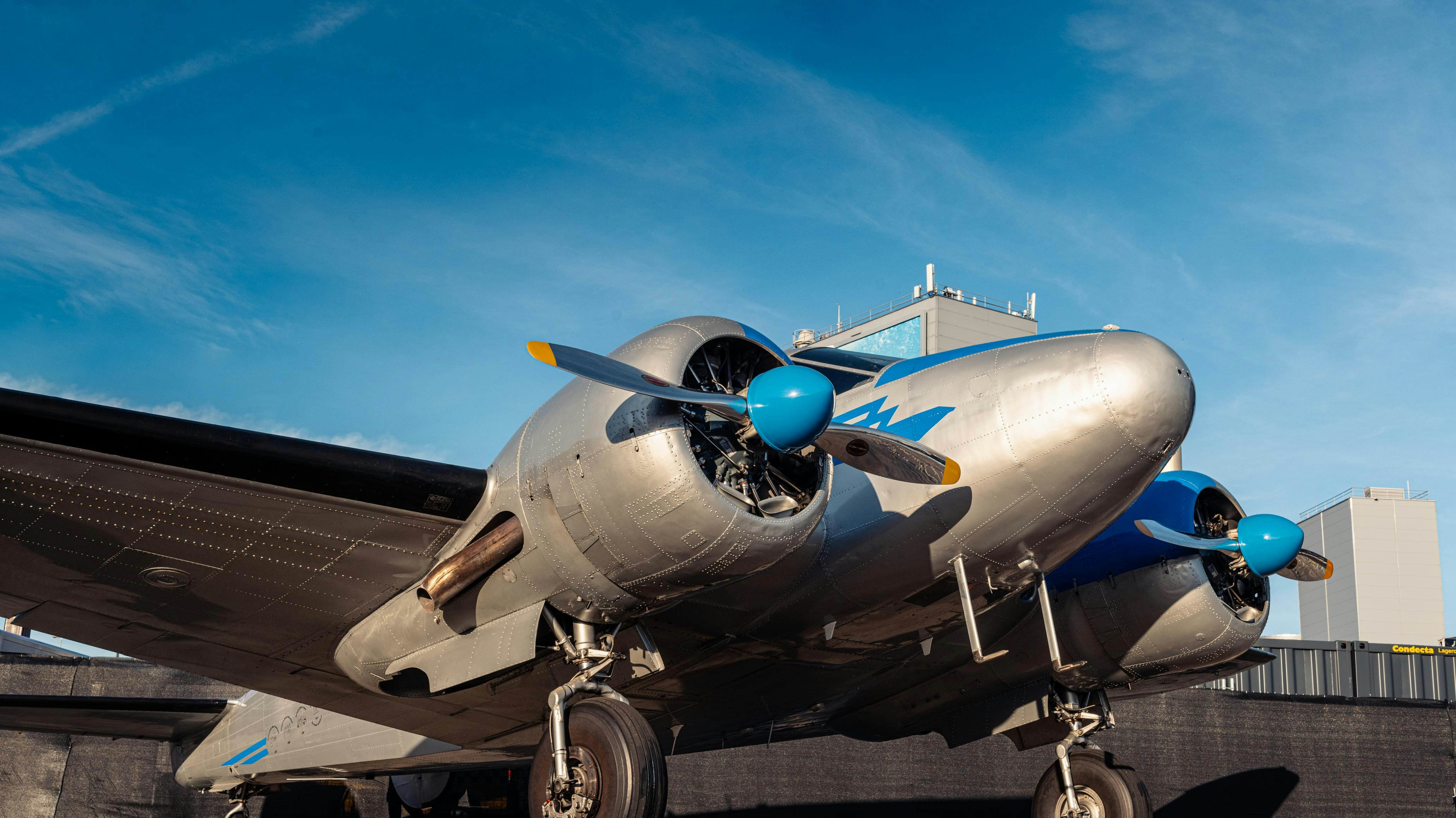 a silver and blue airplane sitting on top of a tarmac