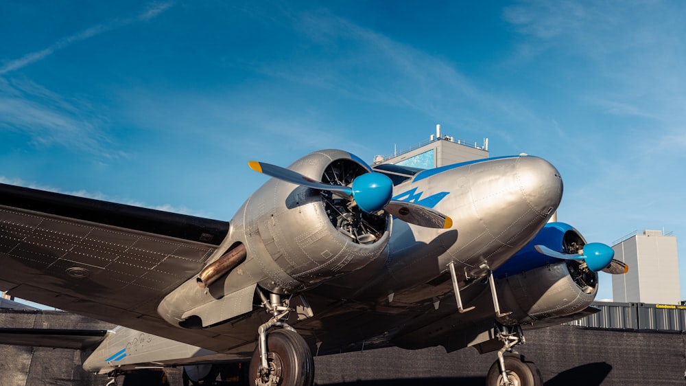 um avião prateado e azul sentado em cima de uma pista