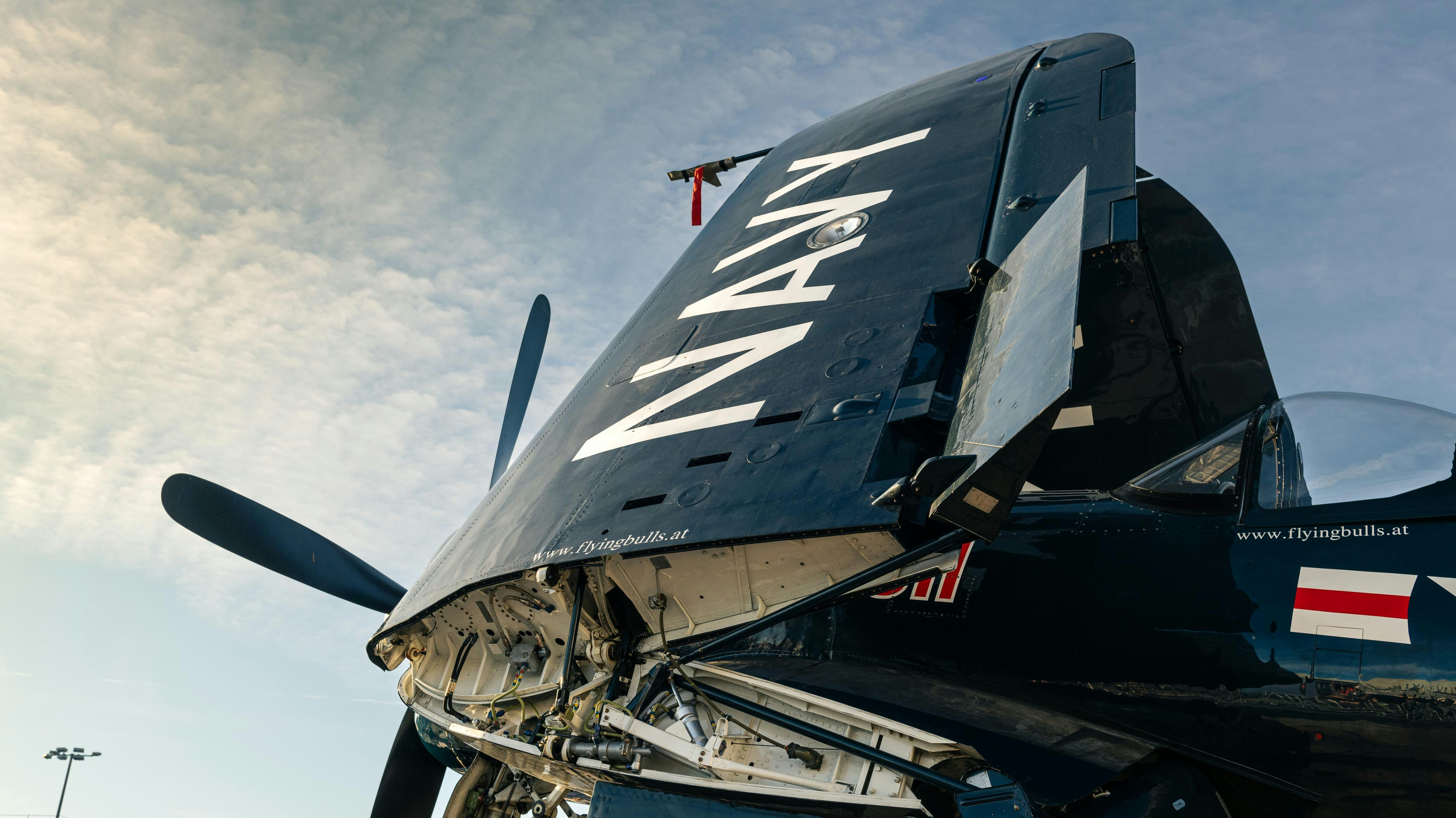 a close up of the nose of an airplane, RedBull Navy Vought F4U stands with wings folded at Zurich airport