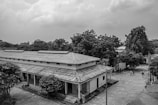 Black and white photo of the original school building from 1954 surrounded by village greenery.