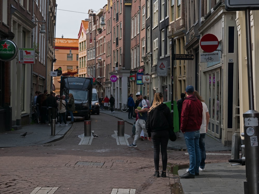 a group of people walking down a street next to tall buildings