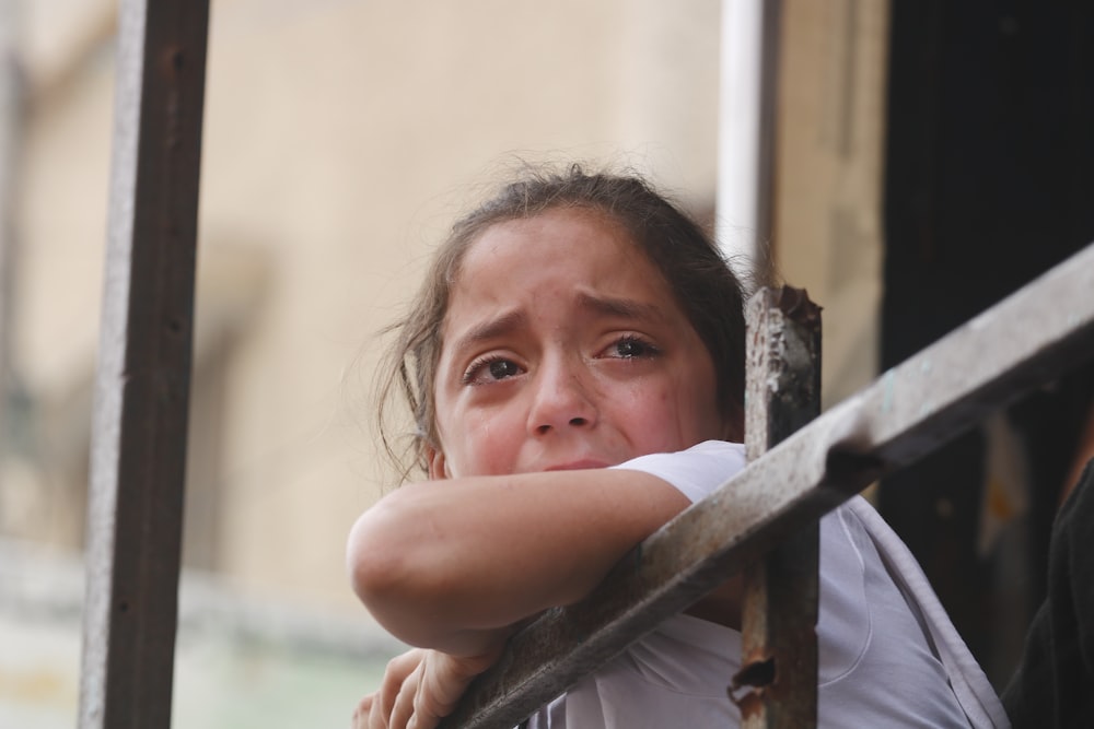a young girl leaning against a rail with her hand on her shoulder