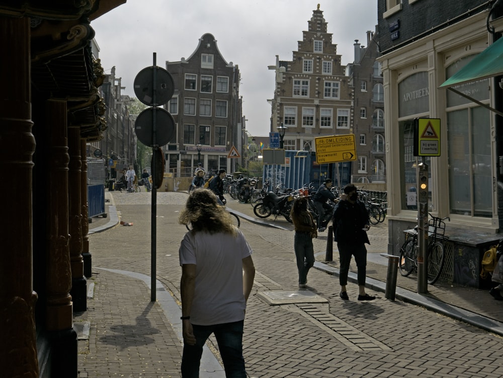 a group of people walking down a street next to tall buildings