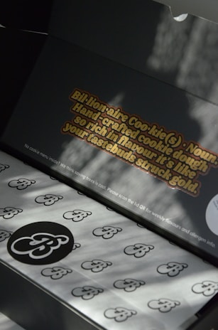 Elegant biscuit boxes open to reveal neatly arranged personalized sablés with minimalist designs.