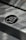 A pattern of stylized 'B' letters is printed on a smooth metallic or paper surface. A large black circle in the center highlights one of the 'B' letters, with smaller ones scattered around it. There's a message at the top regarding saving trees, indicating an environmentally conscious theme.