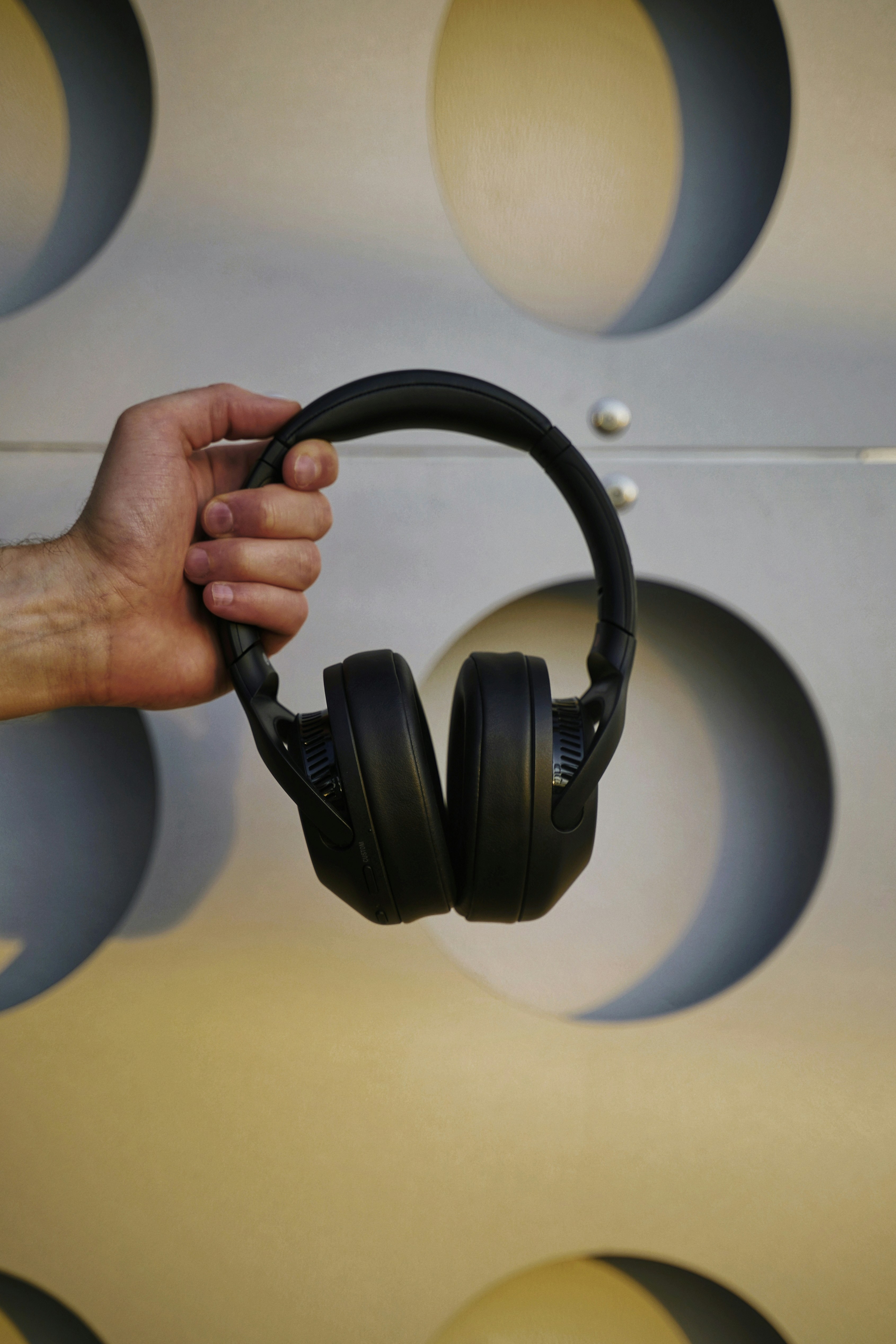a hand holding a pair of black headphones