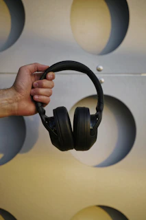 Hands holding headphones and a podcast media kit printed on textured paper with blue and orange accents.