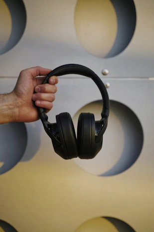 Hands holding headphones and a podcast media kit printed on textured paper with blue and orange accents.
