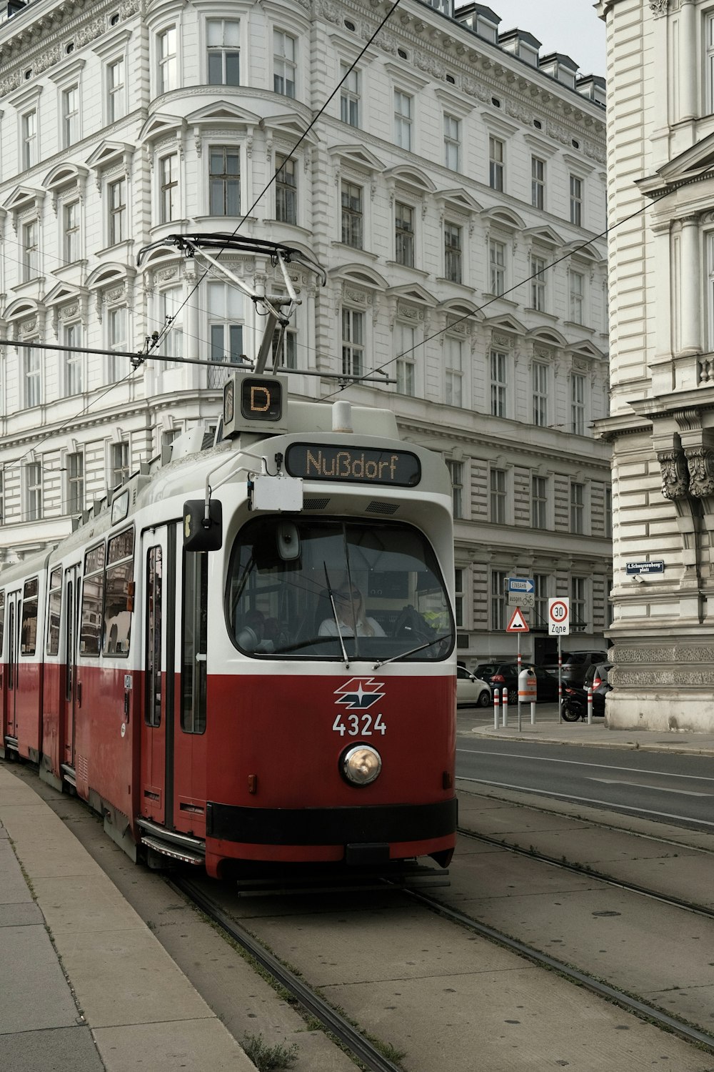 a red and white train traveling past a tall building