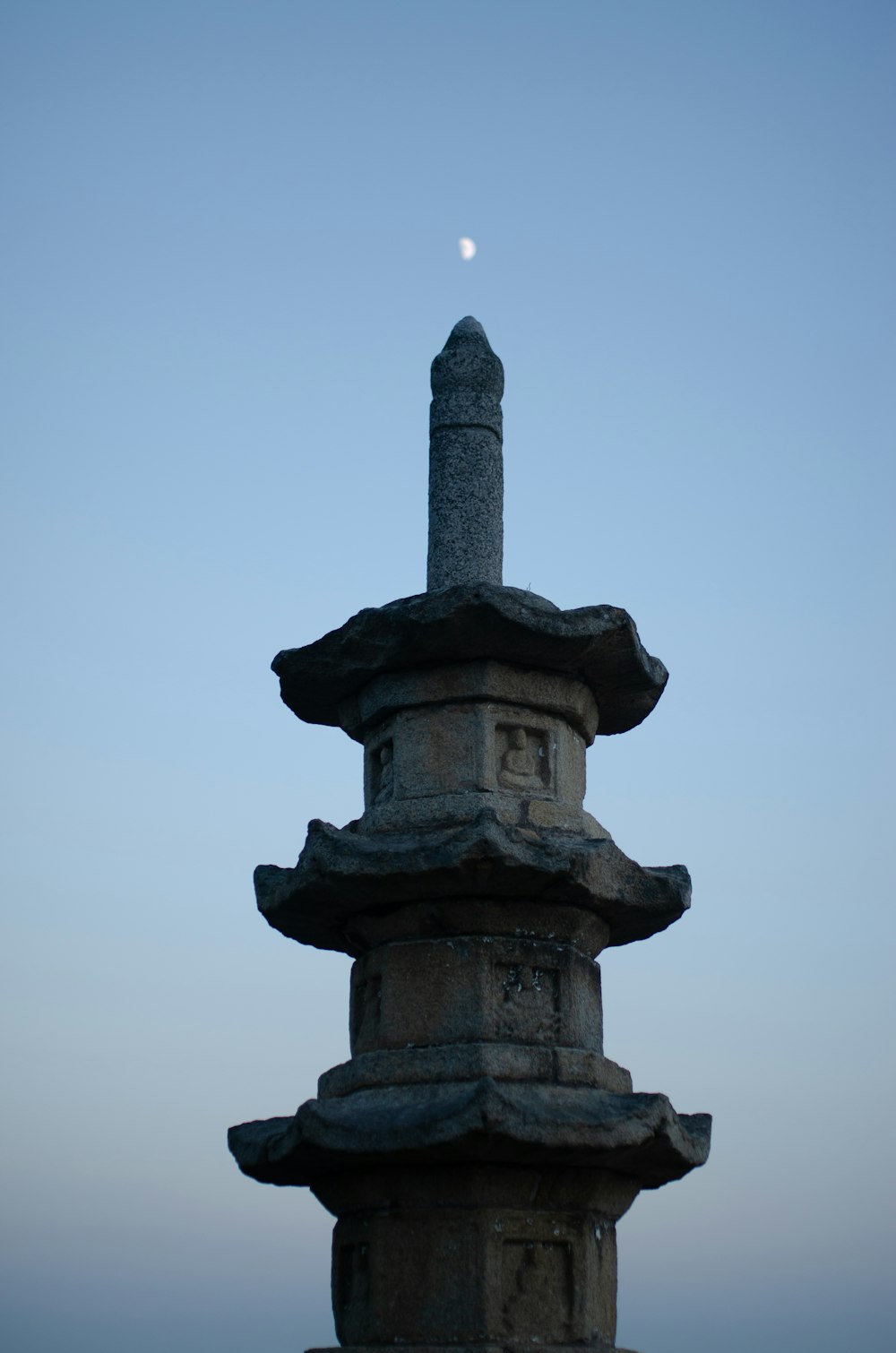 a tall stone tower with a moon in the background