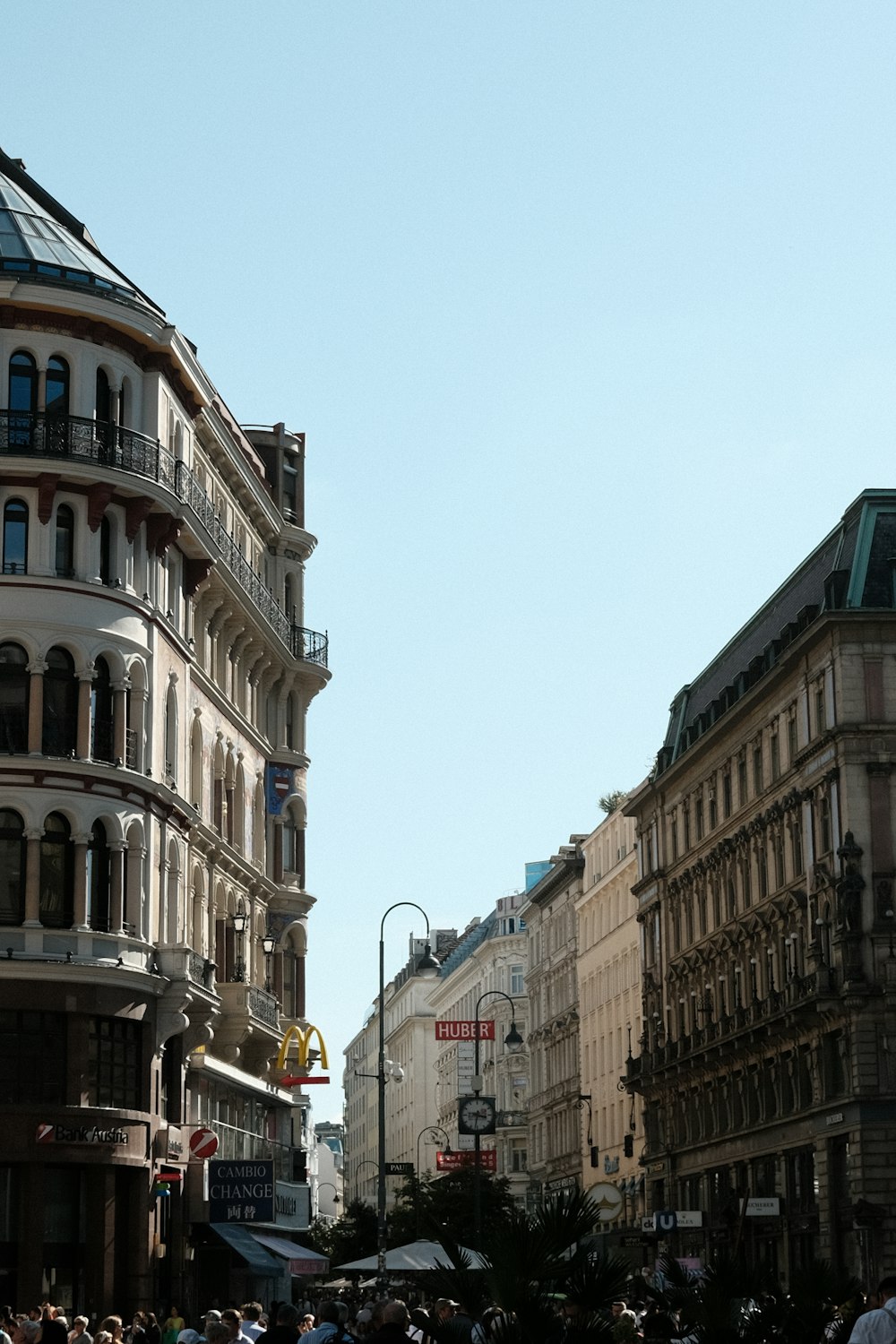 eine Menschenmenge, die eine Straße neben hohen Gebäuden entlanggeht