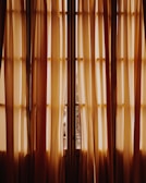 Luxurious cream curtains softly draping a sunlit villa window.