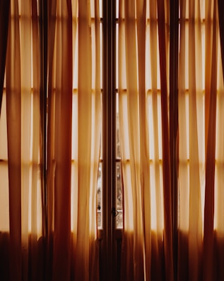 Luxurious cream curtains softly draping a sunlit villa window.