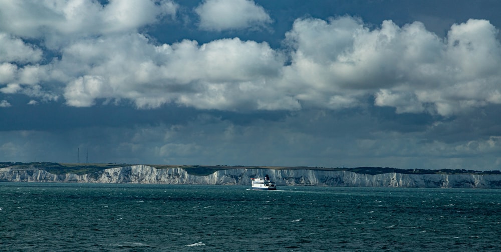 a boat in the water near a large cliff