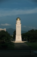 a tall white clock tower sitting in the middle of a park