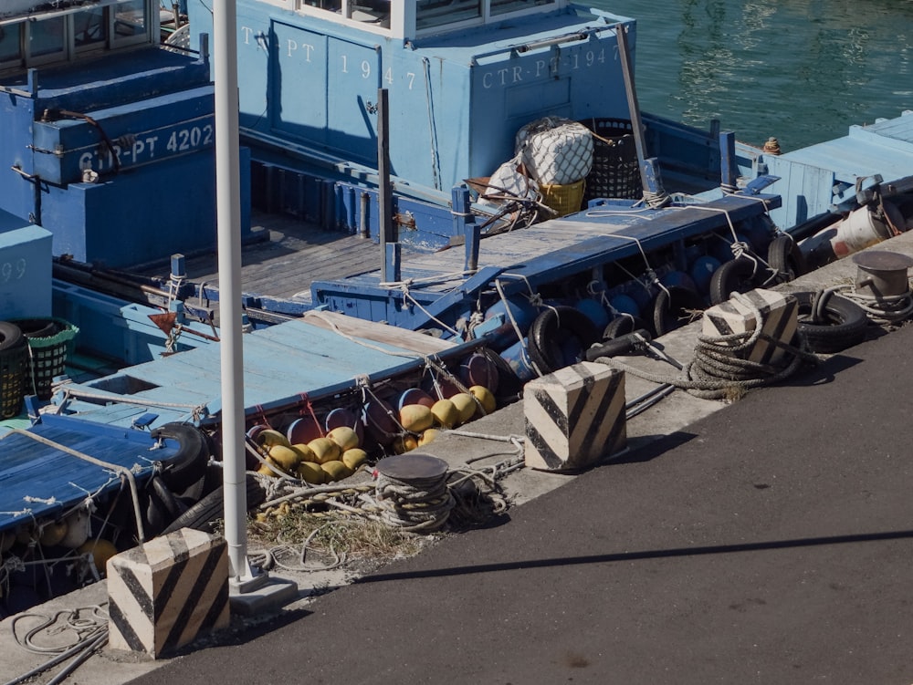 a blue boat docked at a pier next to a body of water