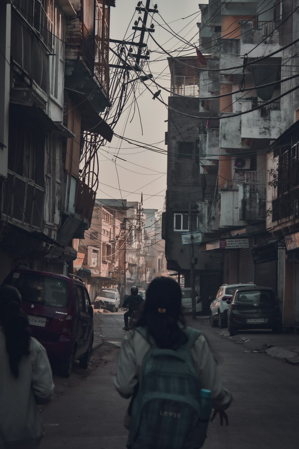 a woman walking down a street next to tall buildings