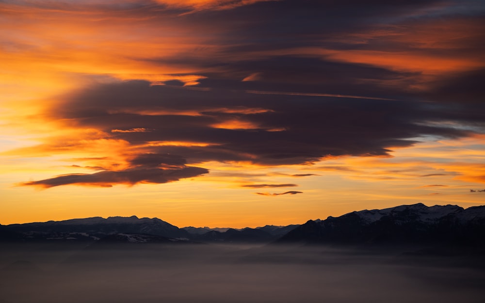 a plane is flying over a mountain range at sunset