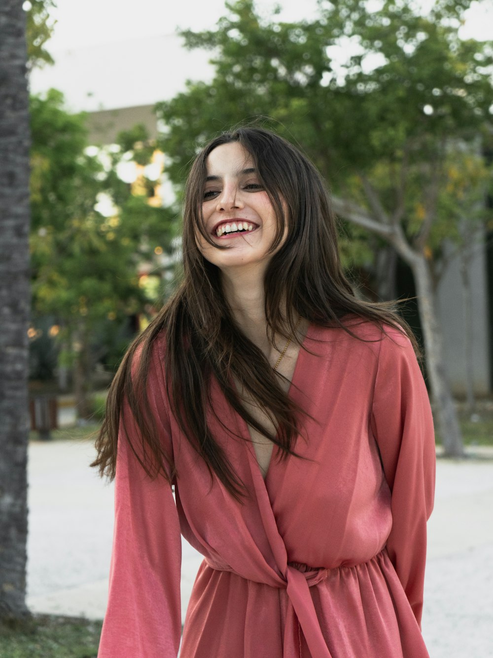 a woman in a pink dress smiles at the camera