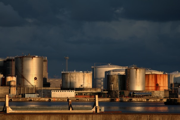 Storage tanks lined up neatly at a petroleum terminal with layered shadows.