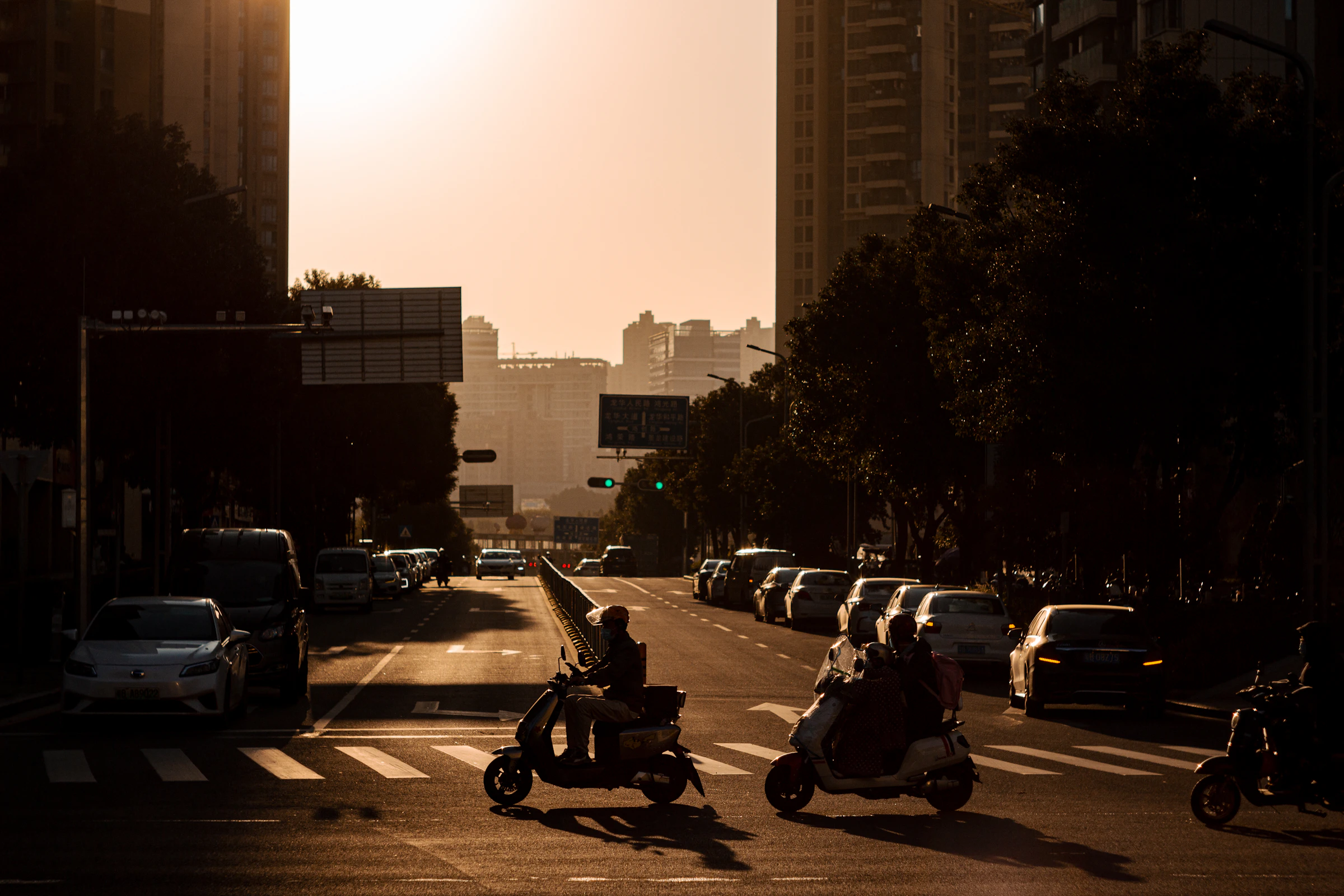 Deux jeunes en scooter / cyclomoteur dans la circulation urbaine au crépuscule