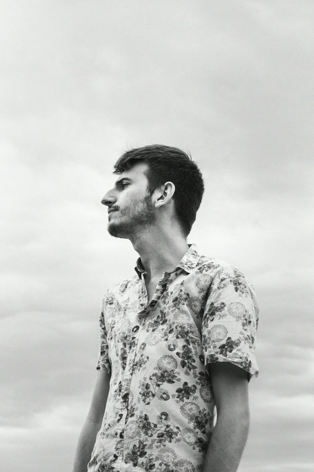 a man in a flowered shirt looks off into the distance