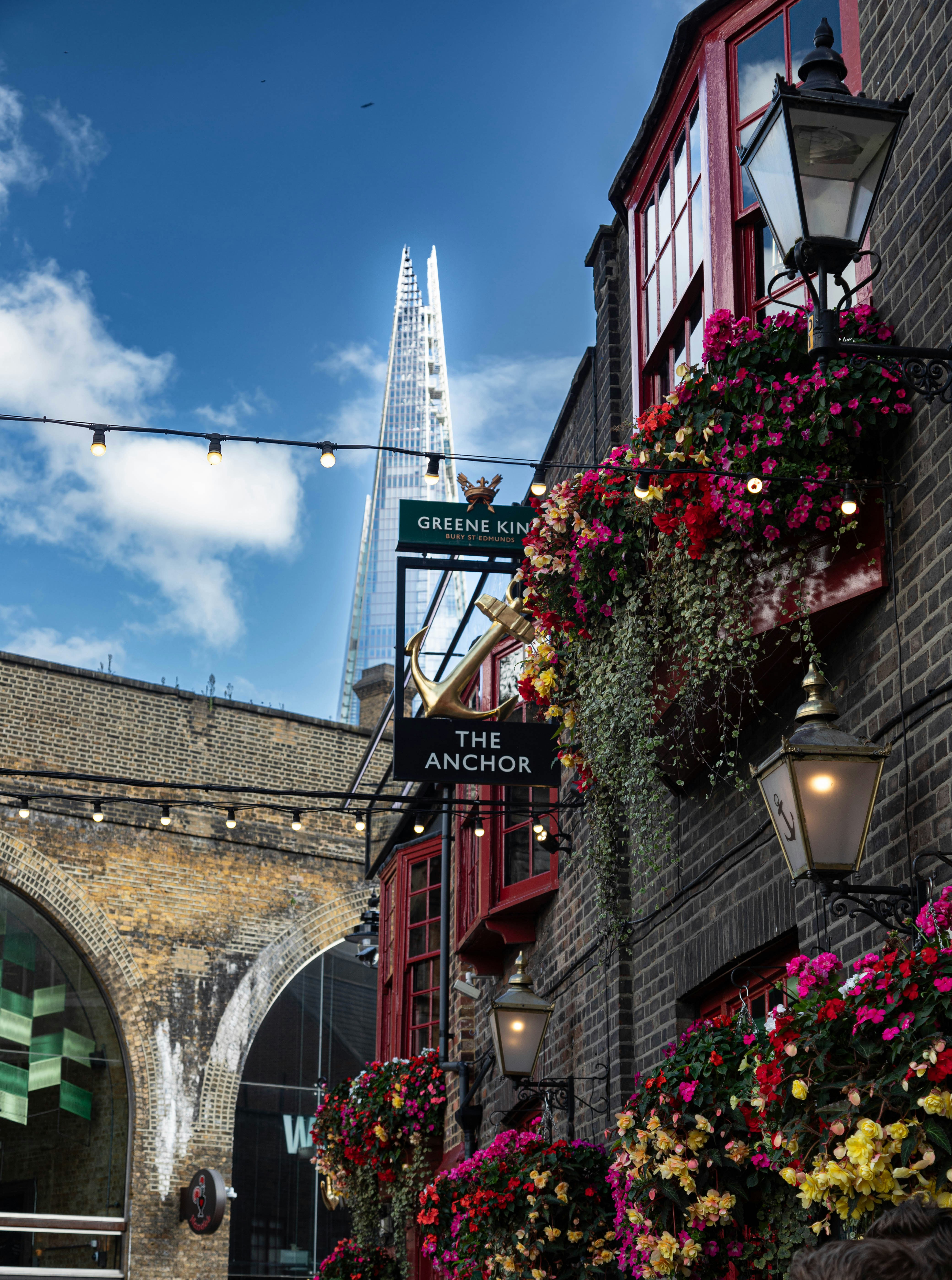 a city street with flowers hanging from the side of buildings