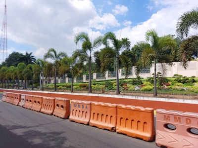 A row of flexible water-filled barriers lined up along a temporary roadwork site under a clear sky.