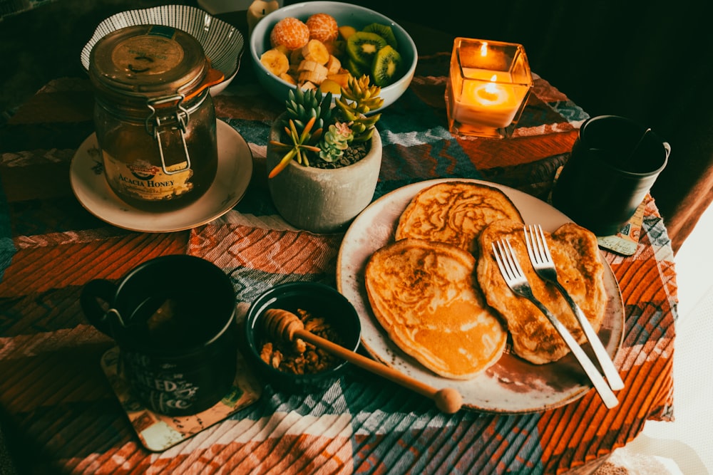 a plate of pancakes and a bowl of fruit on a table