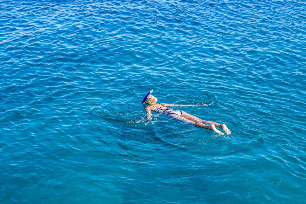 a woman floating in the ocean on a surfboard