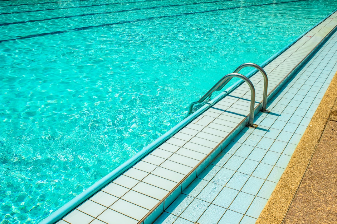 a swimming pool with a long metal railing next to it, swimming pool side with stair vacation season relaxation place con