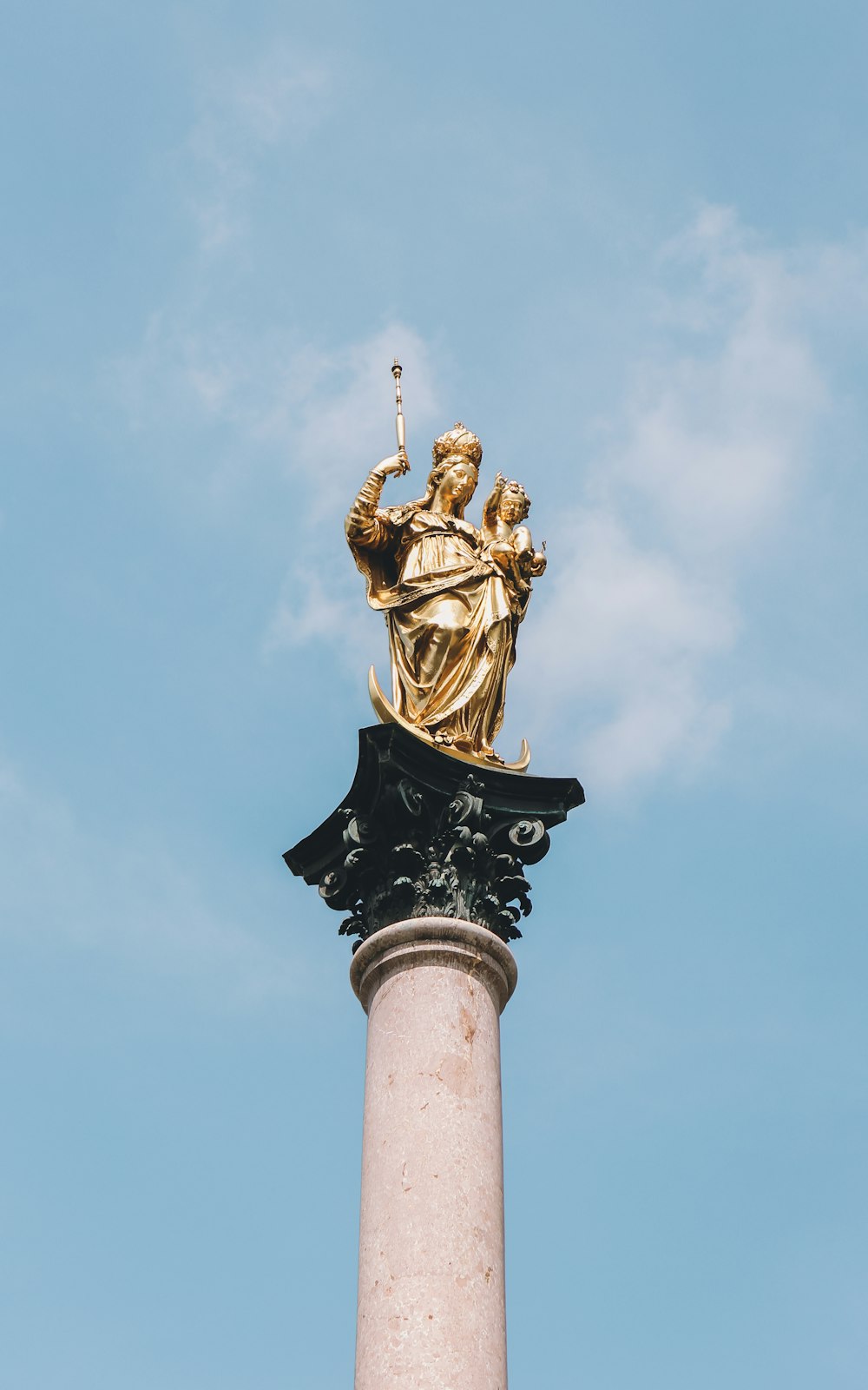 Une statue dorée au sommet d’un pilier blanc
