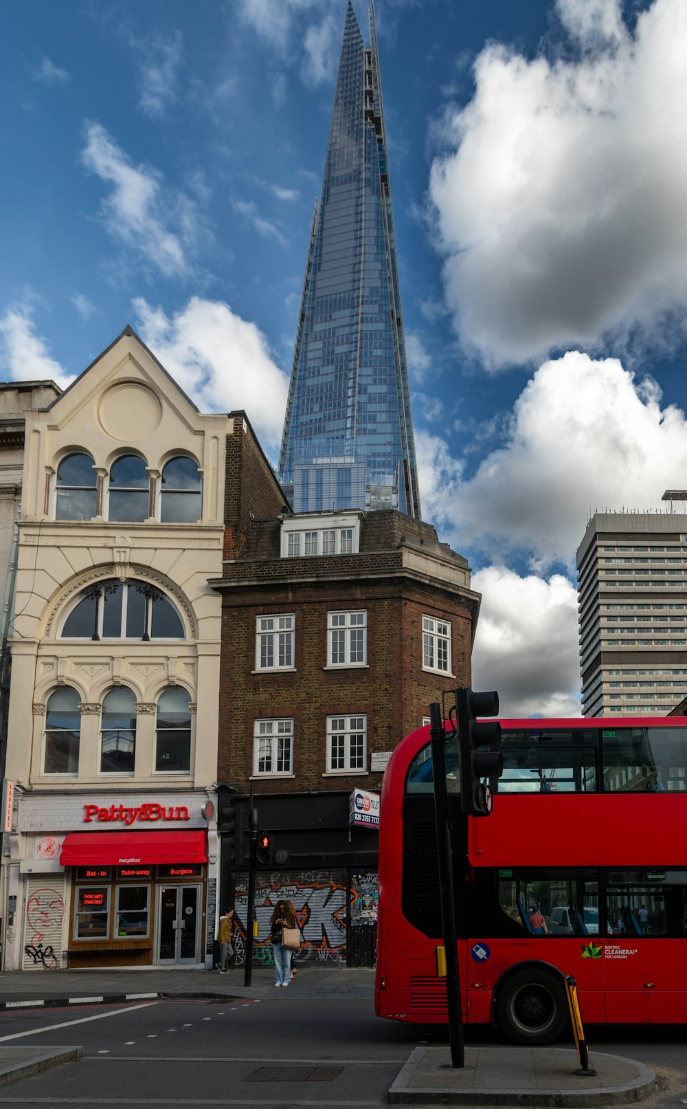 a red double decker bus driving past a tall building