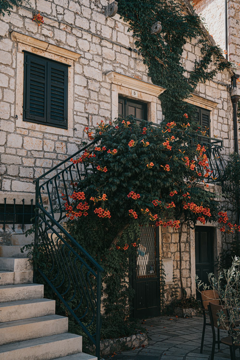 un bâtiment en pierre avec des fleurs qui poussent dessus