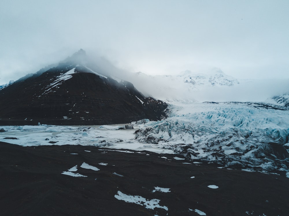 a mountain covered in snow next to a body of water