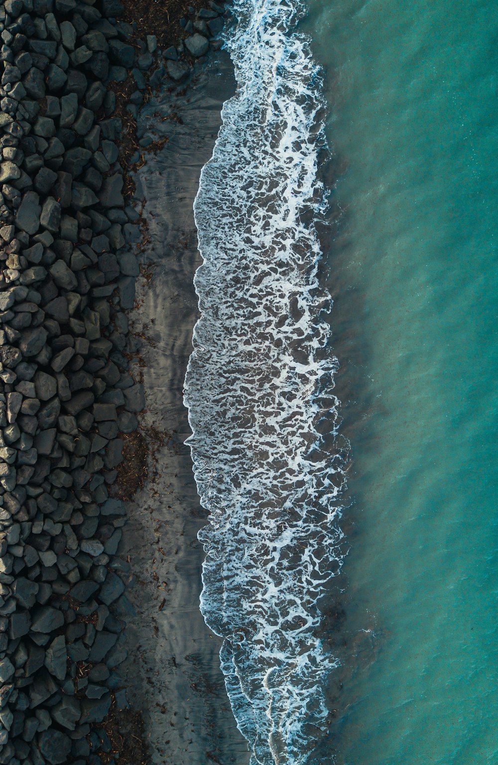 an aerial view of a beach with rocks and water