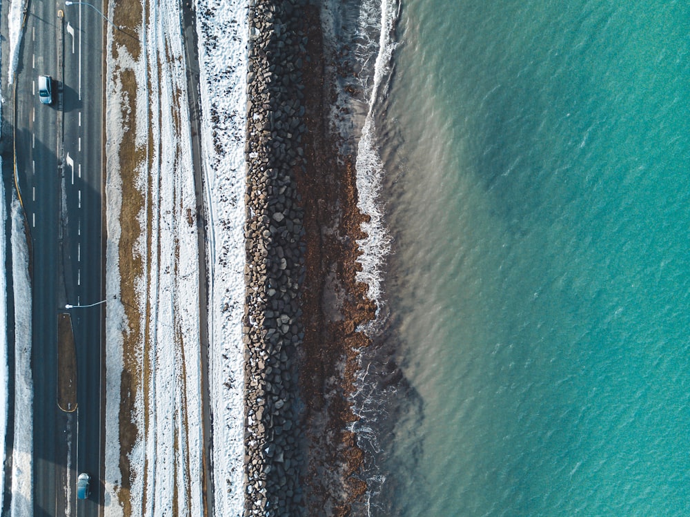 an aerial view of a road next to a body of water